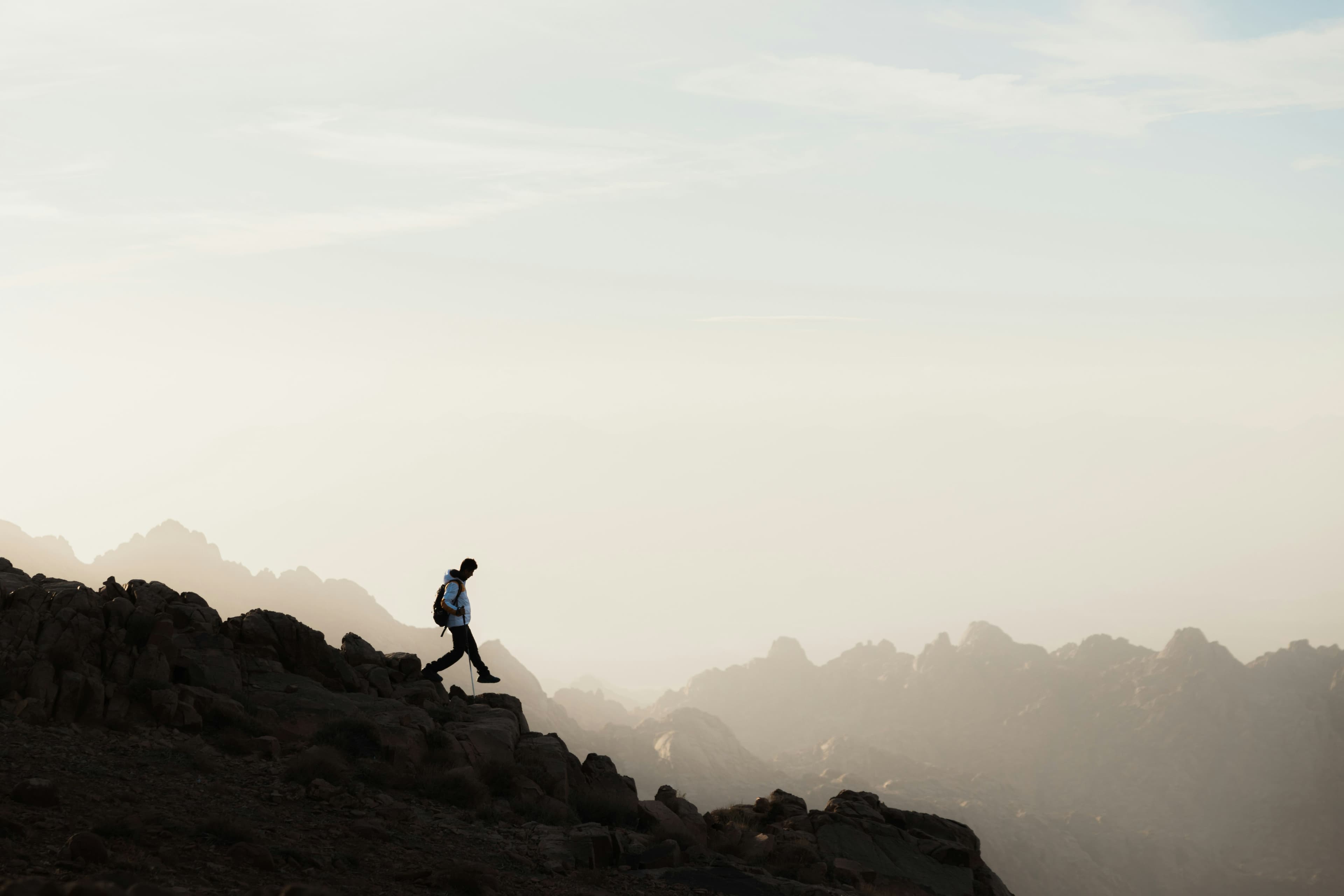 silhouette of a man hiking along the top of a hill